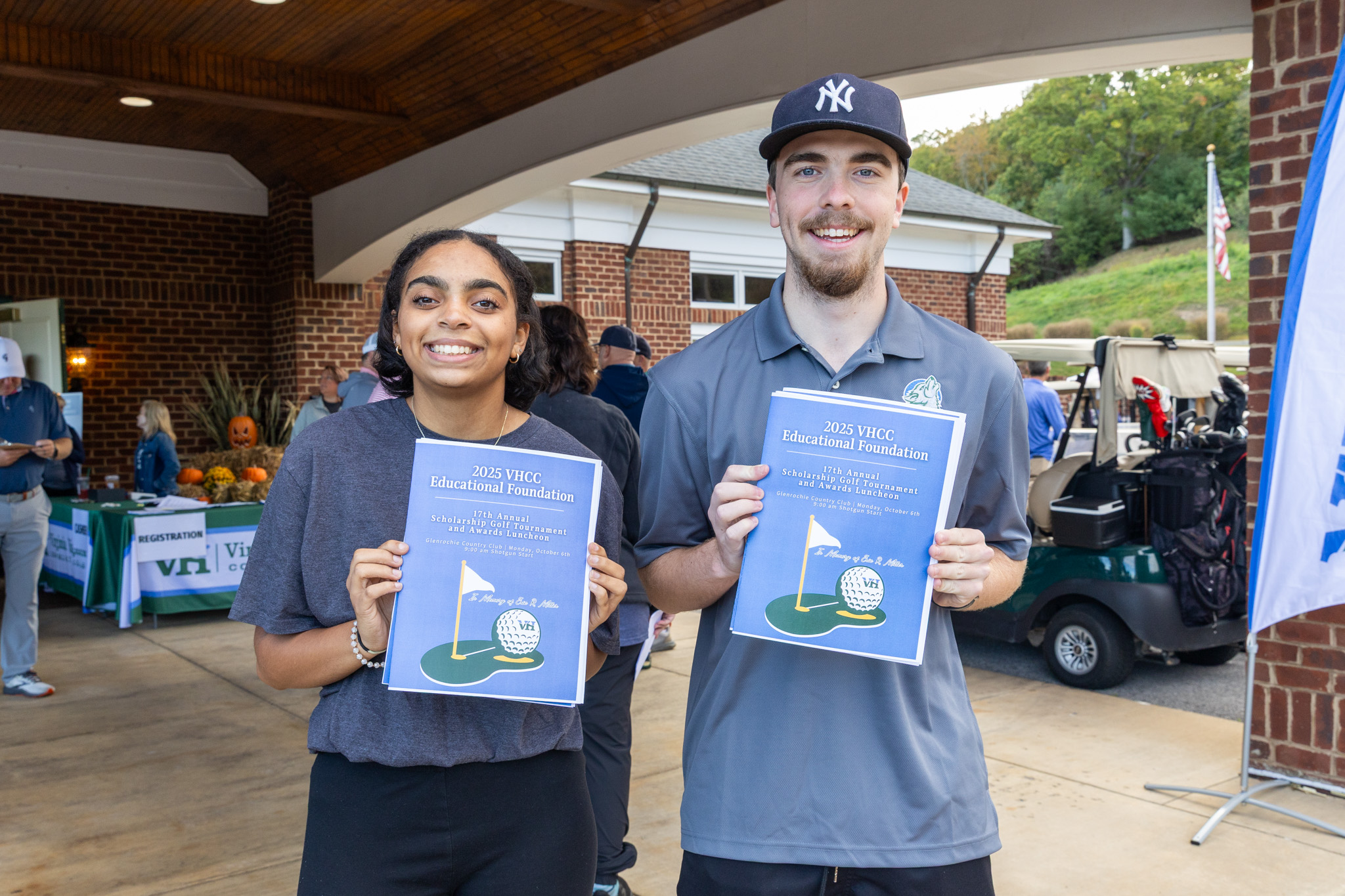 Two Students Holding Programs at Golf Tournament