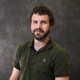 Erick Farris, smiling with a beard, wearing an olive green polo shirt.