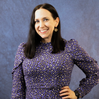 Marie Porterfield, a woman with long dark hair wearing a purple leopard print dress and unique eye-shaped earrings, smiling against a blue textured backdrop.