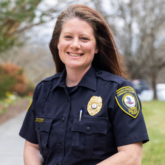 Professional headshot of Nicole Cline, a woman with long brown hair, smiling and wearing a Virginia Highlands Community College Police uniform against a blurred outdoor background.
