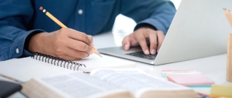 Male using laptop and writing