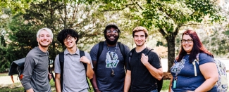 Group of students wearing backpacks and smiling at the camera