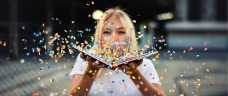 Student Blowing Confetti off of a book